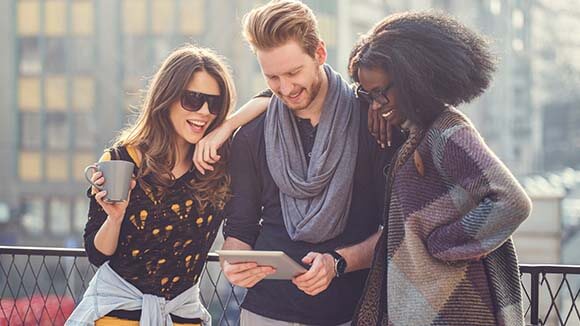 Friends search on tablet for career advice, outside with blurred background