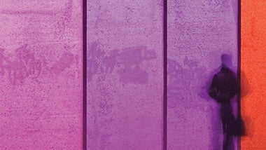 purple and pink wall with dark grey shadowed person standing against it