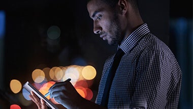Man checking the salary survey on his tablet at night